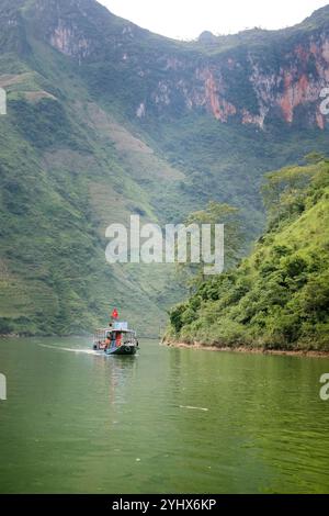 Ein Boot auf dem Fluss Nho Que in der Provinz Ha Giang, Vietnam. Der Fluss schlängelt sich durch die hohen Kalksteinklippen des Geoparks Dong Van Karst Plateau Stockfoto