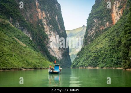 Ein Boot auf dem Fluss Nho Que in der Provinz Ha Giang, Vietnam. Der Fluss schlängelt sich durch die hohen Kalksteinklippen des Geoparks Dong Van Karst Plateau Stockfoto