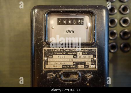 Nahaufnahme eines analogen Landys+Gyr-Stromzählers, der Kilowattstunden anzeigt, mit einem Metallgehäuse, das mechanische Ziffernblätter anzeigt Stockfoto
