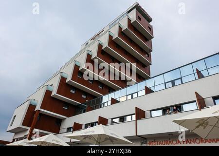 Modernes architektonisches Design eines eckigen Hotelgebäudes mit markanten Balkonen vor bewölktem Himmel, Štrbské pleso, Slowakei Stockfoto