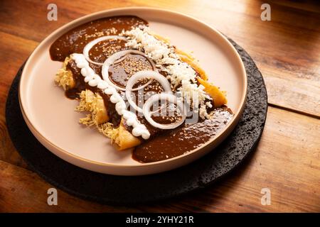 Enmoladas Hühnchen. In Mexiko werden sie Enchiladas de Mole Poblano genannt, Maistortillas gefaltet und mit gehacktem Huhn gefüllt, das in einer Sauce c gebadet wird Stockfoto