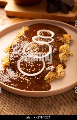 Enmoladas Hühnchen. In Mexiko werden sie Enchiladas de Mole Poblano genannt, Maistortillas gefaltet und mit gehacktem Huhn gefüllt, das in einer Sauce c gebadet wird Stockfoto