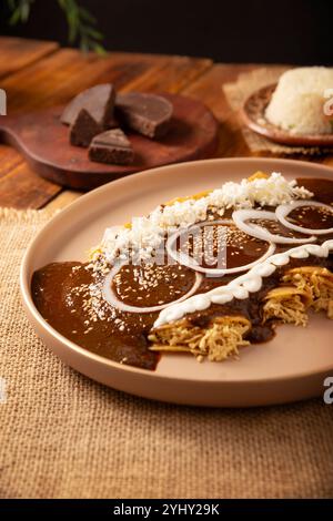 Enmoladas Hühnchen. In Mexiko werden sie Enchiladas de Mole Poblano genannt, Maistortillas gefaltet und mit gehacktem Huhn gefüllt, das in einer Sauce c gebadet wird Stockfoto