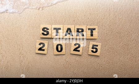 Holzblöcke mit Text von Anfang 2025 auf Strand Sand Hintergrund. Happy New Year Concept oder Silvester Celebration Stockfoto