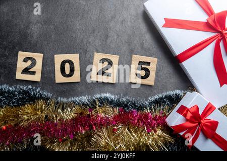 Menschliche Hand mit einer Zahl von 2025 mit farbigem Hintergrund. Happy New Year Concept oder Silvester Celebration. Collage-Kunst Stockfoto