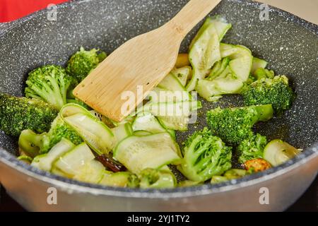 Brokkoli und Zucchini werden in heißem Öl gerührt und vermischen Aromen und Aromen zu einer lebendigen, gesunden Zubereitung. Stockfoto