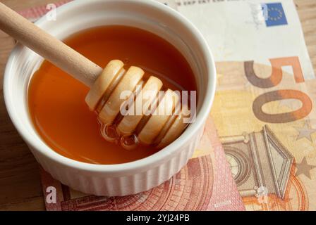 Honigschale mit verstreuten Bienenpollen und Kamille, die natürliche Gesundheit und Süße symbolisiert. Stockfoto