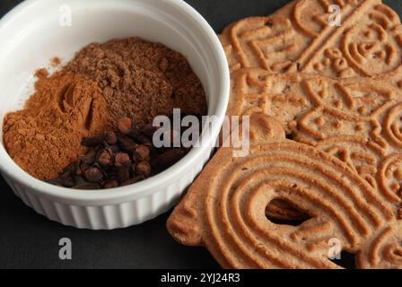 Zimt-Weihnachtsplätzchen mit Gewürzen auf dunkelblauem Hintergrund für ein gemütliches Weihnachtsgefühl. Stockfoto