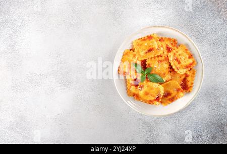 Ravioli mit Ricotta, frischer Tomatensoße und frischem Basilikum auf grauem Hintergrund. Draufsicht. Kopierbereich Stockfoto