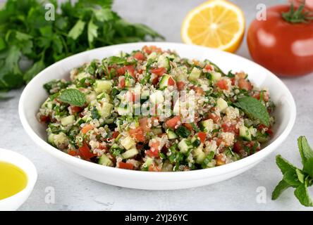 Veganer vegetarischer Salat mit Quinoa, Tomaten, Gurken, Petersilie, Zitrone und Dressing. Makro. Stockfoto