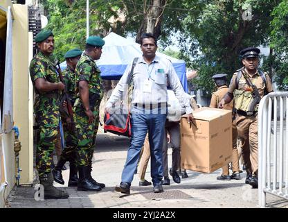 Colombo, Sri Lanka. November 2024. Wahlbeamte und ein Polizeibeamter tragen einen Tag vor der Parlamentswahl in Colombo, Sri Lanka, am 13. November 2024 eine Wahlurne und andere Wahlmaterialien. Sri Lanka wird seine Parlamentswahlen am 14. November abhalten und alle notwendigen Vorbereitungen getroffen, um einen fairen und transparenten Prozess zu gewährleisten, kündigte der Vorsitzende der Wahlkommission R.M.A.L. Ratnayake am Dienstag an. Die Abstimmung findet am Donnerstag von 7.00 bis 16.00 Uhr Ortszeit in über 13.000 Wahllokalen im ganzen Land statt. Quelle: Ajith Perera/Xinhua/Alamy Live News Stockfoto