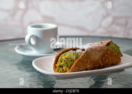 Sizilianische Pistazien-Cannoli mit Puderzucker, serviert auf weißem Teller mit Espresso-Kaffee, traditionellem italienischem Gebäck Dessert Stockfoto