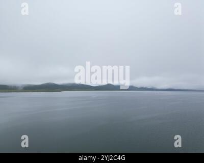 Misty Lake Landschaft mit Bergen und einem bewölkten Himmel, die eine ruhige Atmosphäre schaffen Stockfoto