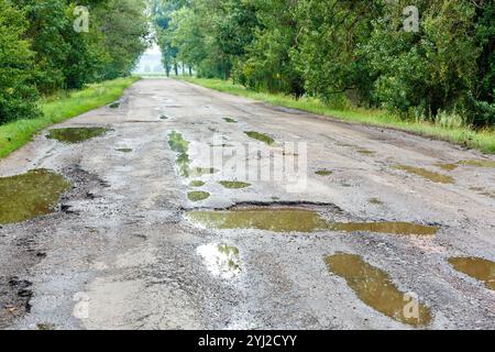 Schlaglöcher auf der Straße mit Steinen auf dem Asphalt. Die Asphaltoberfläche wird auf der Straße zerstört. Schlechter Zustand der Straße, muss repariert werden. Aufbau A Stockfoto