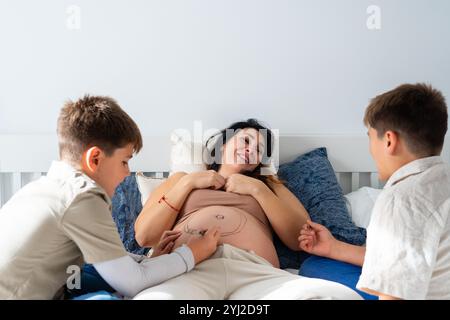 Kaukasische Familie von schwangeren Müttern und ihren beiden Kindern, die ihren Bauch malen Stockfoto