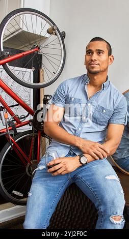 Mann, der an einem an der Wand montierten Fahrrad sitzt. Stockfoto