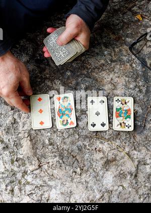 Hände legen Spielkarten auf einer felsigen Oberfläche im Freien aus, Italien Stockfoto