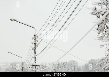 Stangen und Drähte sind mit Schnee und Eis bedeckt. Die Stromleitung war mit Schnee bedeckt. Vorstellung von Stromproblemen und -Ausfällen während der Winterschneestunde Stockfoto