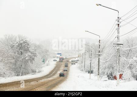 Stadtverkehr im Winter. Auf einer verschneiten Autobahn fahren Autos schnell auf einer rutschigen Straße. Gefahr von Schneefall, Schneestürmen, schlechtem Winterwetter. Ort c Stockfoto