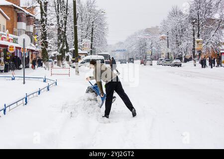 Ukraine, die Stadt Romny, 18. Januar 2018: Ein Mann entfernt an einem verschneiten Wintertag Schnee von den Straßen der Stadt. Städtische Schneeräumung und Menschen Stockfoto