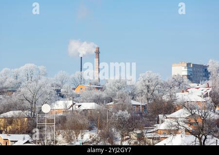 Das Rohr eines Gaskesselhauses in der Stadt vor dem blauen Himmel. Weißer Rauch kommt aus dem gemauerten Kamin. Heizraum im Winter. Luftverschmutzung. Cen Stockfoto