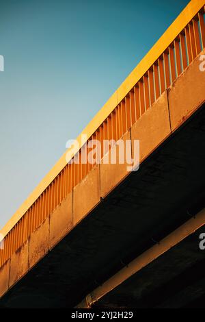 Niedriger Winkel auf alte abgenutzte Betonbrücke mit gelbem Metallschutzzaun, selektiver Fokus Stockfoto