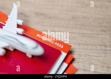 Ein Reisepass mit Bordkarten und ein Spielzeugflugzeug auf einem Holztisch, symbolisiert Reisen und Abenteuer. Stockfoto