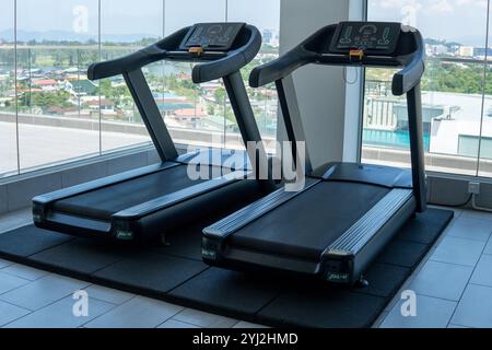 Zwei Laufbänder in einem modernen Fitnessstudio mit Blick auf ein großes Fenster und Stadtblick. Fitnesskonzept. Stockfoto