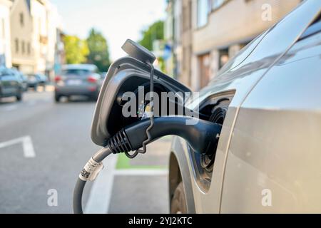 Elektroauto wird tagsüber an einer Straßenladestelle aufgeladen. Stockfoto