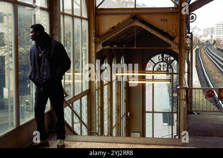 Ein Mann steht kontemplativ in einem Bahnhof, dessen Gleise sich in die Ferne erstrecken, Berlin Stockfoto