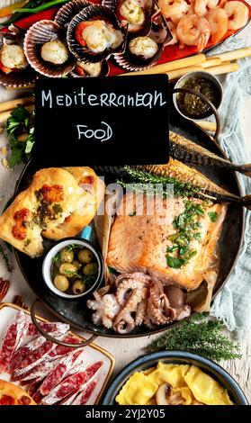 Auswahl verschiedener mediterraner Speisen - Fisch, Garnelen, Meeresfrüchte, Ravioli, Gemüse auf weißem Hintergrund. Draufsicht. Stockfoto