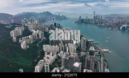 Ein Panoramablick fängt die atemberaubende Skyline und das geschäftige urbane Leben rund um die Victoria Bay in Hongkong ein, umgeben von üppigem Grün Stockfoto