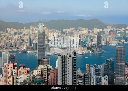 Ein Panoramablick fängt die geschäftige Stadt und das ruhige Wasser der Victoria Bay in Hongkong ein und hebt die berühmte Skyline und die fernen Berge hervor. Stockfoto