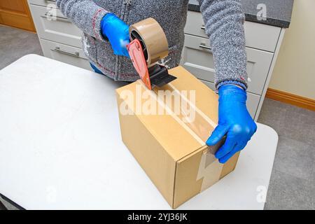 Brauner Karton wird mit einem Bandspender versiegelt Stockfoto