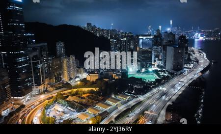 Ein atemberaubender Blick auf Hongkong bei Nacht mit beleuchteten Wolkenkratzern, gewundenen Straßen und einer lebhaften urbanen Atmosphäre. Stockfoto