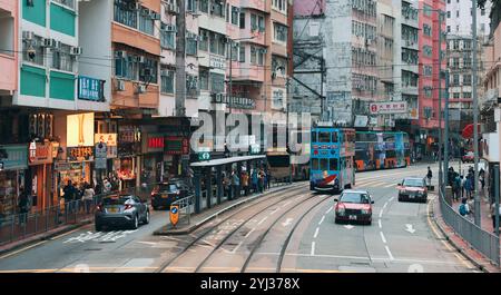 Die geschäftige Straße mit Straßenbahnen, Autos und Fußgängern in Hongkong zeigt das tägliche Leben und den lebhaften lokalen Handel. Stockfoto