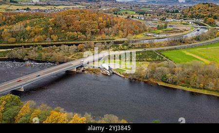 Hydro Ness Wasserkraftwerk am Ufer des Flusses Ness Schottland, Holm Mills Road Bridge, Caledonian Canal und Hügel mit herbstlichen Bäumen Stockfoto