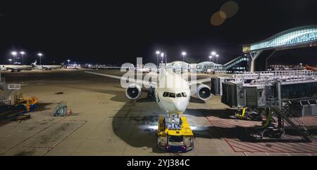 Ein Passagierflugzeug wird am Flughafen Hongkong unter hellen Flughafenlichtern gewartet und für seinen nächsten Flug vorbereitet. Stockfoto