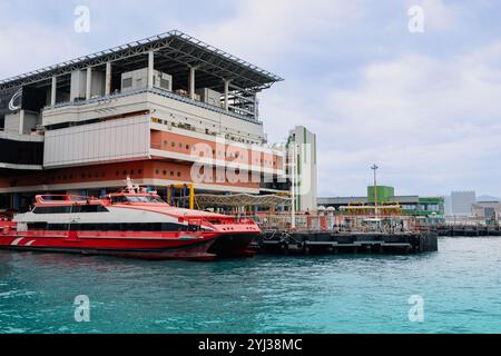 Die Fähren legen an einem belebten Terminal in Hongkong an und bereiten sich bei klarem Himmel auf die Abfahrten nach Macau vor. Stockfoto