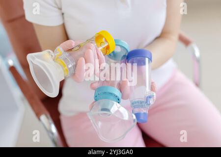 Arzt in rosafarbenen chirurgischen Handschuhen hält Asthma-Inhalator-Aerosol-Spacer in den Händen. Inhalationskammer-Silikonmaske zur Kinderbehandlung Atemwegsinfe Stockfoto