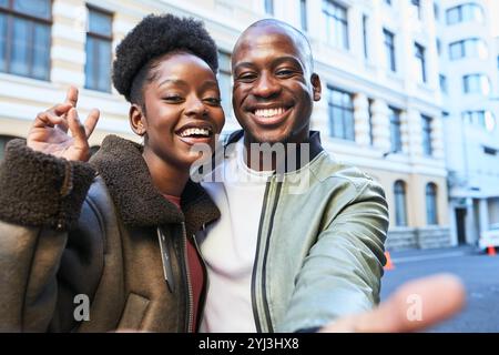 Ein lächelndes Paar macht an einem lebhaften Tag ein lustiges Selfie im Herzen der Stadt Stockfoto