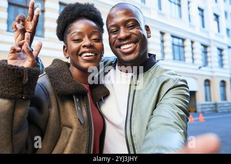 Glückliches Paar, das Selfie in urbaner Umgebung nimmt, lächelt und an einem sonnigen Tag ihre gemeinsame Zeit genießt Stockfoto