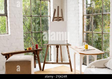 Kunststudio mit leerer Leinwand auf Staffelei umgeben von Farben und Pinseln, zu Hause Stockfoto