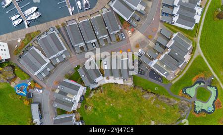 Aus der Vogelperspektive auf ein Wohngebiet mit modernen Häusern, Straßen und einem Yachthafen mit Booten. Das Bild zeigt einen Spielplatz und Grünflächen, die urba hervorheben Stockfoto