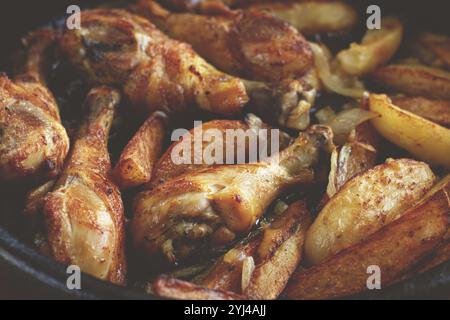 Gebratene Hähnchenkeulen mit Kartoffelscheiben, in einer Tonpfanne, gebacken im Ofen, mit Gewürzen, hausgemacht, keine Leute Stockfoto