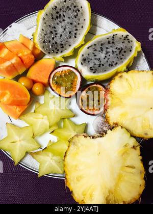 Ein kunstvoll angeordneter Teller mit einer lebhaften Auswahl an tropischen Früchten, einschließlich Ananas, Drachenfrüchten und Sternfrüchten, die ein Gefühl von Frische wecken Stockfoto