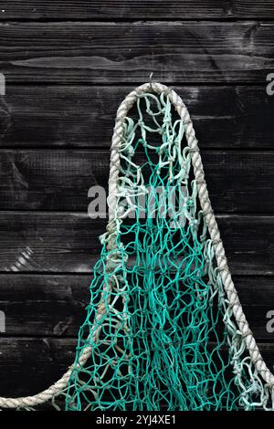 Fischernetze hängen zum Trocknen an einer alten schwarzen Holzwand als Hintergrund Stockfoto
