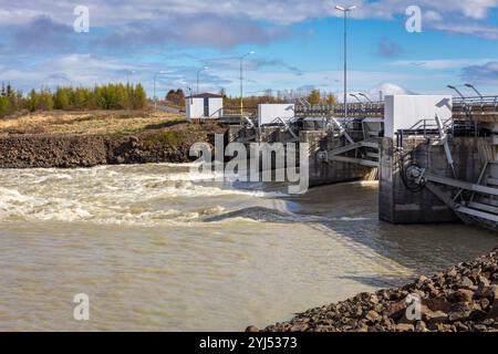 Staudamm des Wasserkraftwerks Lagarfossvirkjun am Fluss Lagarfljot, Island. Braunes Gletscherwasser, das vom Damm stürzt. Stockfoto