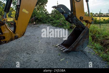 Die Straße ist nach einem plötzlichen Sturm in Missouri unpassierbar. Die Schaufel eines großen Baggerladers wird bei der Reinigung von großem Nutzen sein. Stockfoto