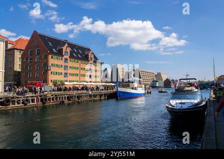 Am 29. April 2023 laufen die Menschen in Kopenhagen, Dänemark, vorbei an bunten Fassaden und alten Schiffen entlang des Nyhavn-Kanals. Stockfoto